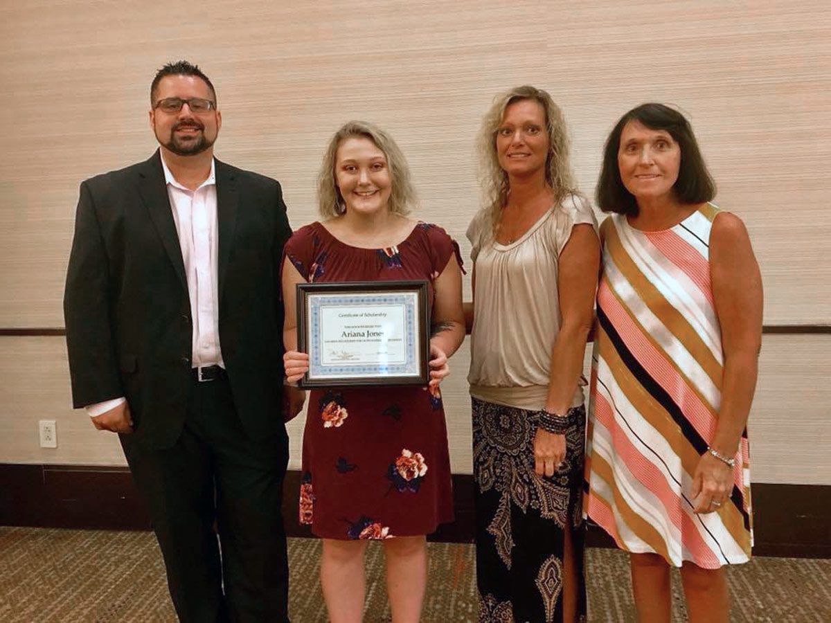 A scholarship recipient holding her certificate with GPHA members